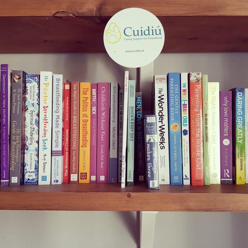 A book shelf with lots of books relating to birth, parenting and breastfeeding.